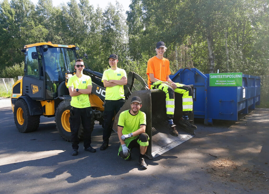 Jäteaseman työntekijöitä työkoneen edessä.