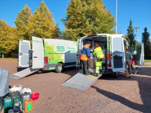 Kymenlaakson Jätteen työntekijä ottaa vastaan asukkaan vaarallisia jätteitä aurinkoisena syyspäivänä.